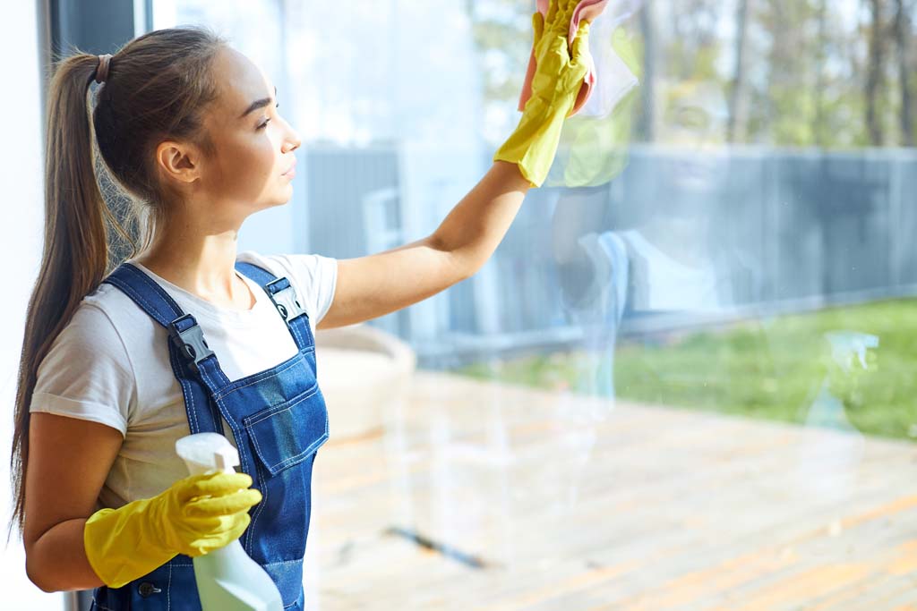 Junge Damen reinigt das Fensterglas
