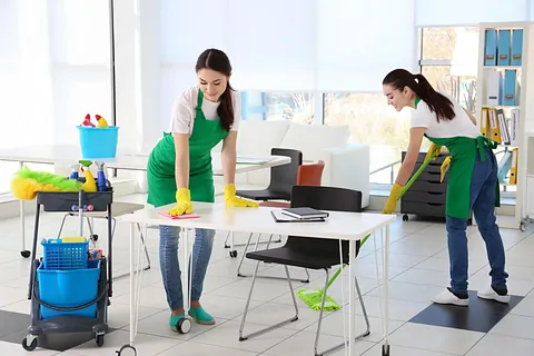 2 Reinigungskräfte reinigen den Tisch